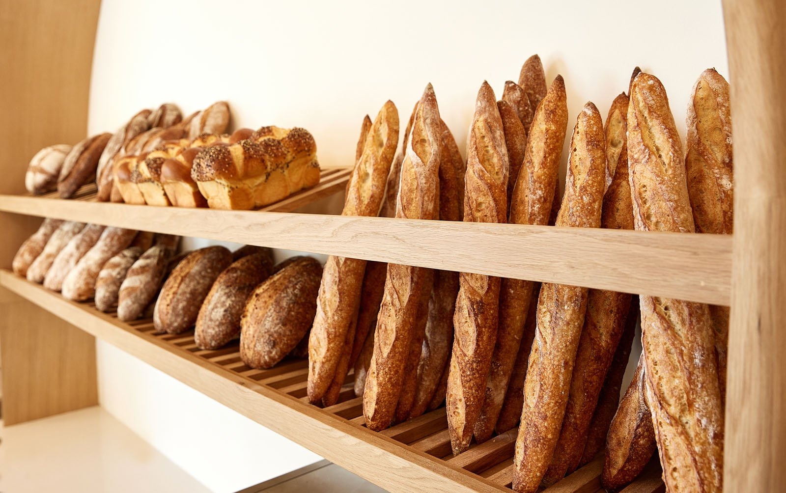 A wall of various breads - baguettes, challah, sourdough, and more 