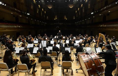 Conservatory students performing in an orchestra facing the conductor