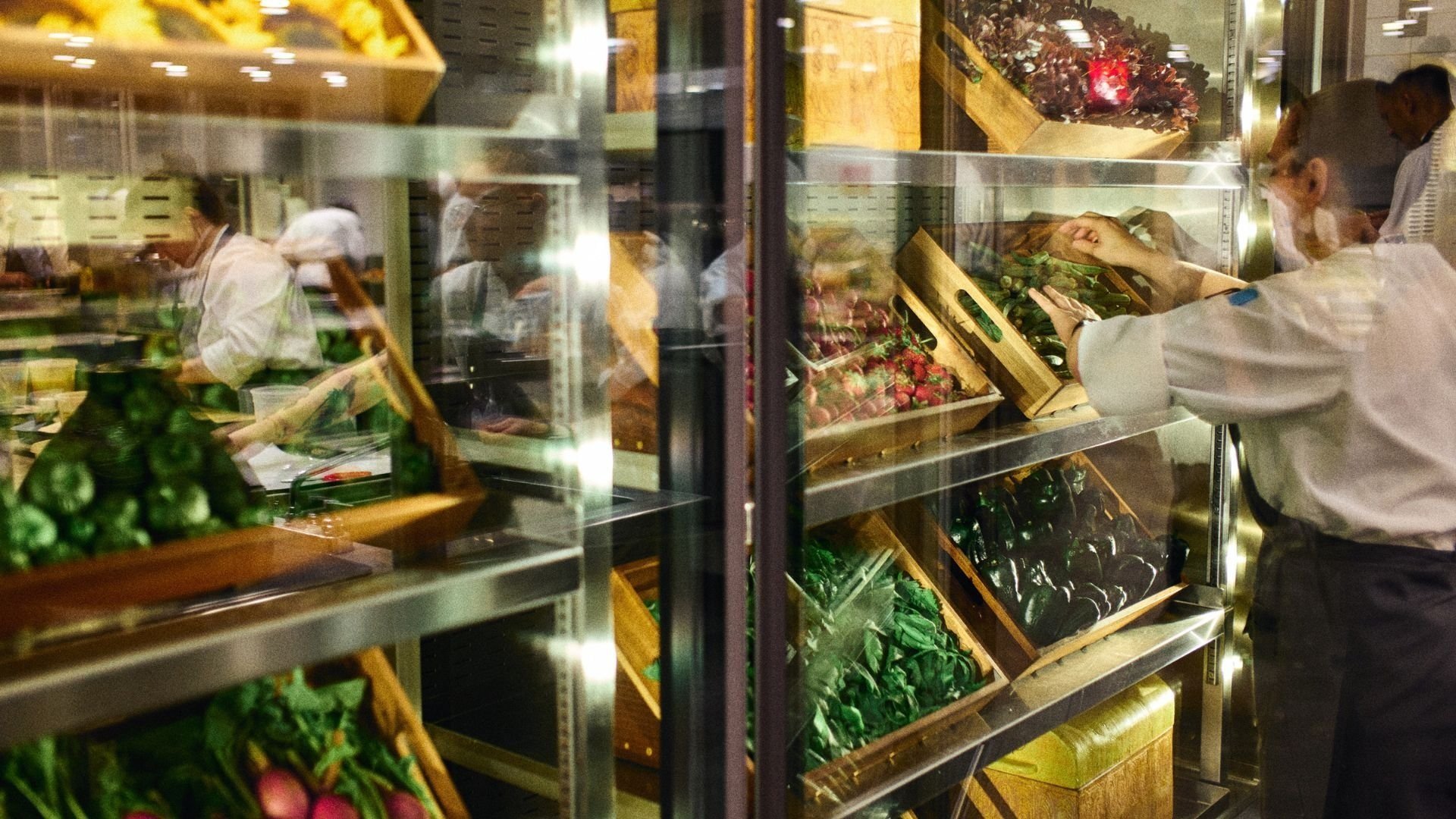 Sous Chef in the kitchen stocking fridges with fresh produce