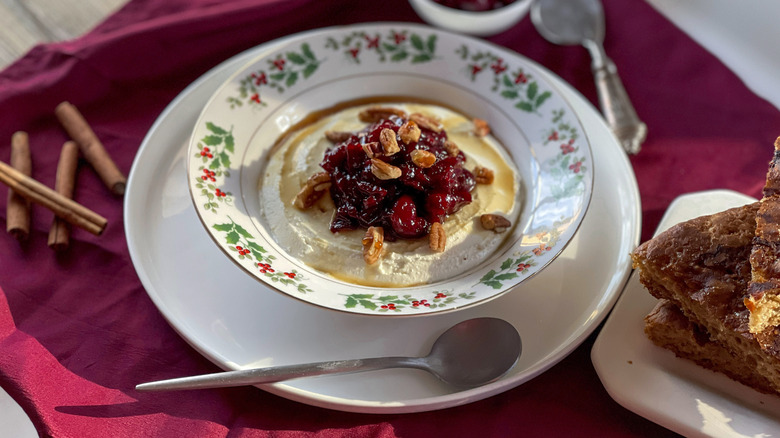 cranberry-cheese spread in a holly-patterned bowl on a burgundy napkin